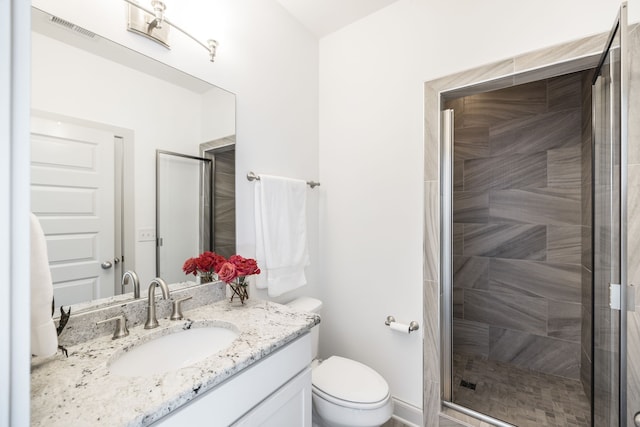 bathroom featuring vanity, a shower with shower door, and toilet