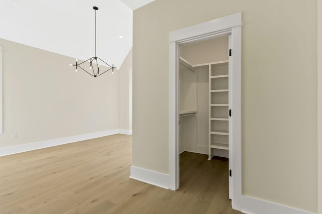 spacious closet with an inviting chandelier and wood-type flooring