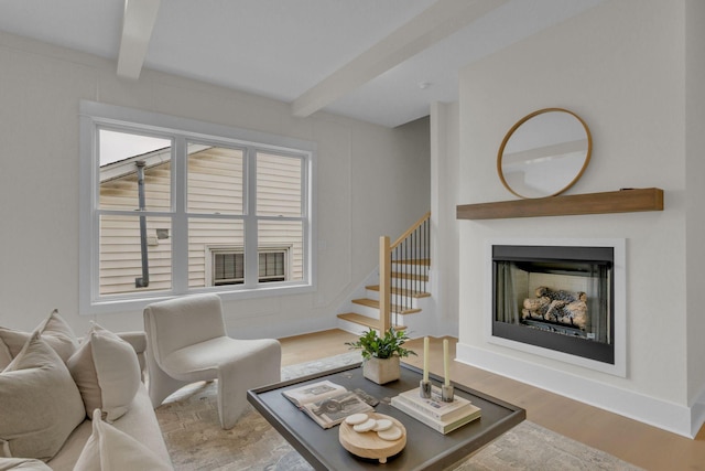 living room featuring beamed ceiling and light hardwood / wood-style floors