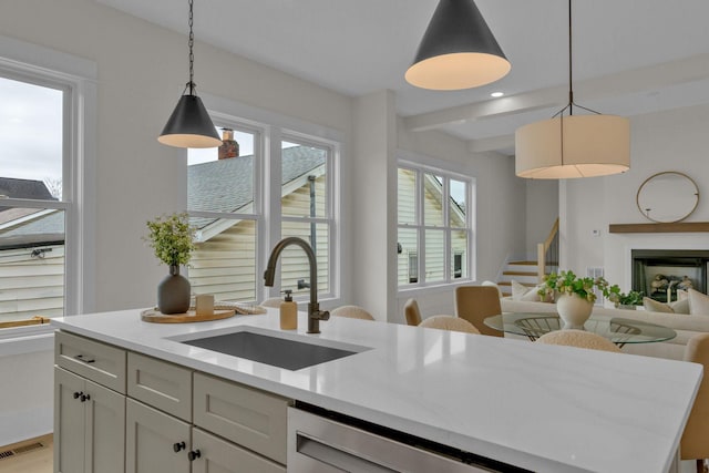 kitchen with decorative light fixtures, white cabinetry, sink, a center island, and light stone counters