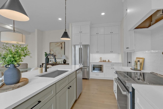 kitchen with hanging light fixtures, appliances with stainless steel finishes, sink, and white cabinets