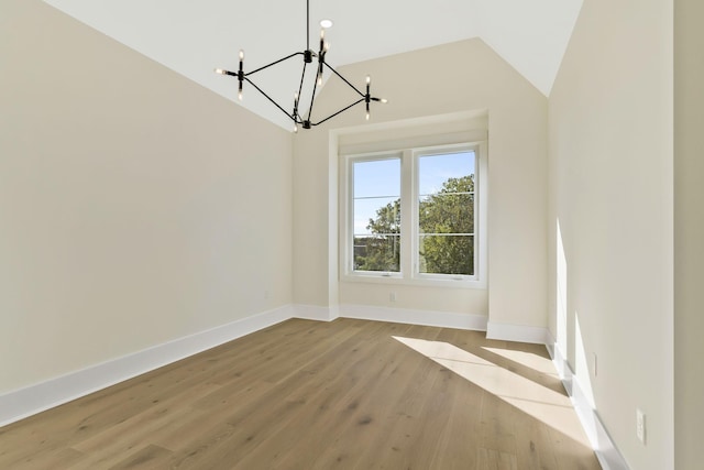 unfurnished dining area with an inviting chandelier, vaulted ceiling, and light hardwood / wood-style flooring