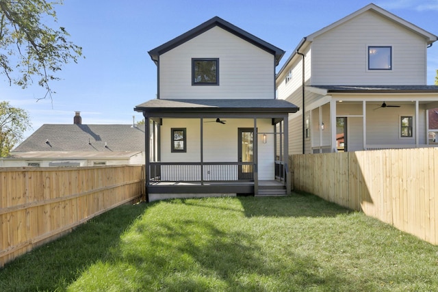 back of property with a yard, ceiling fan, and a porch