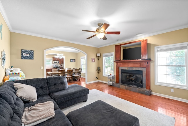 living room featuring ceiling fan, ornamental molding, a fireplace, and hardwood / wood-style floors