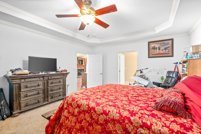 bedroom featuring ceiling fan, ornamental molding, a tray ceiling, and carpet flooring