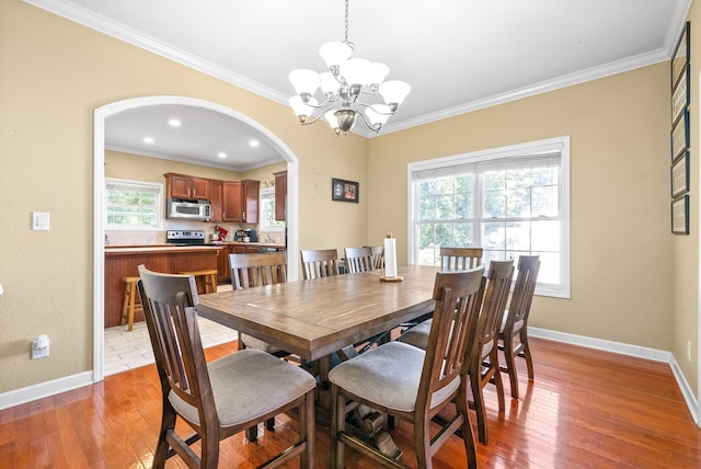 dining space with wood-type flooring, a notable chandelier, and crown molding