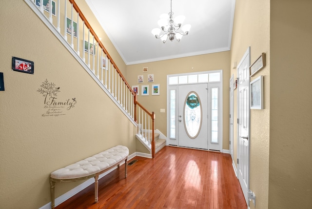 foyer with hardwood / wood-style flooring, a chandelier, and ornamental molding