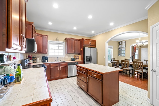 kitchen featuring stainless steel appliances, ornamental molding, a center island, and tile counters