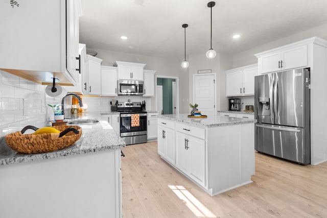 kitchen featuring stainless steel appliances, sink, a center island, and white cabinetry