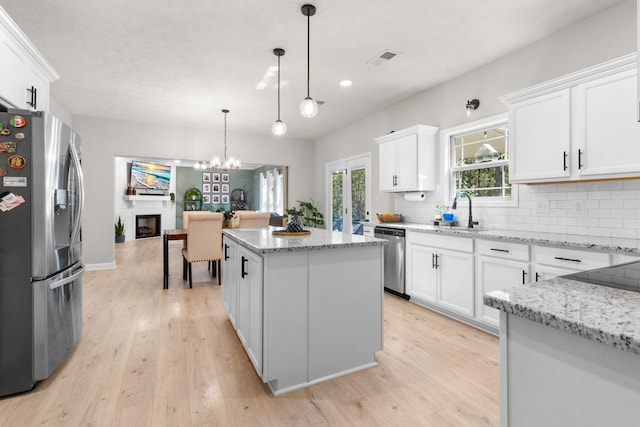 kitchen with sink, appliances with stainless steel finishes, a kitchen island, and white cabinetry