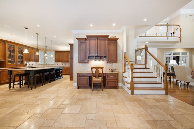 kitchen featuring ornamental molding, pendant lighting, a kitchen bar, and a center island