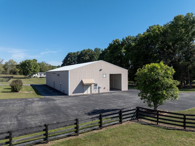 view of outdoor structure featuring a garage, a yard, and a rural view