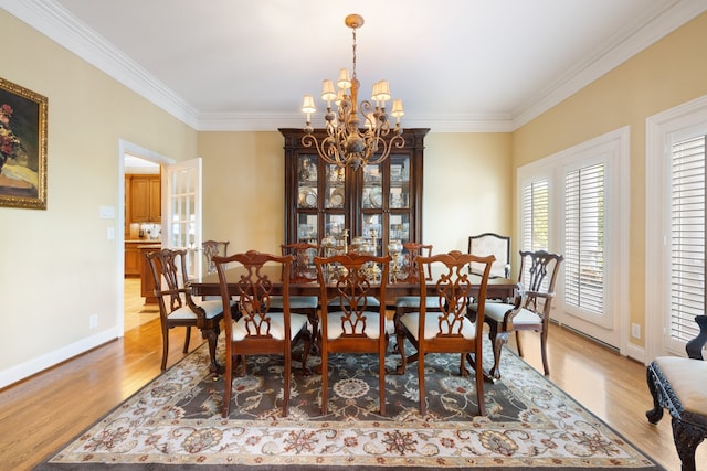 dining area with ornamental molding, a chandelier, and light hardwood / wood-style floors