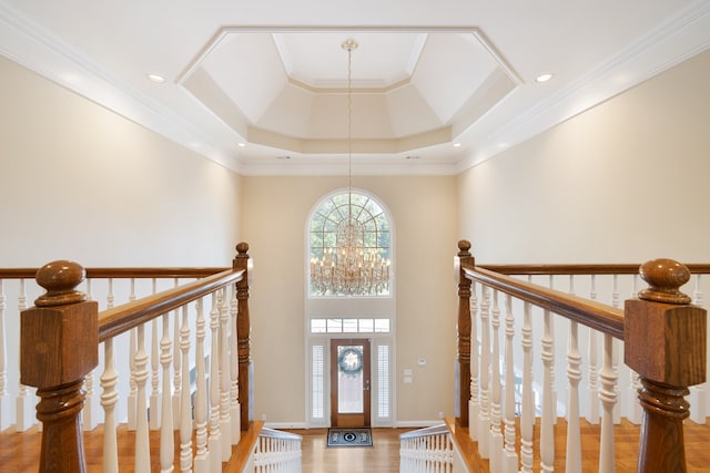 foyer entrance featuring crown molding, hardwood / wood-style floors, an inviting chandelier, and a raised ceiling