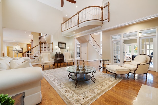 living room with wood-type flooring, ornamental molding, french doors, and a high ceiling