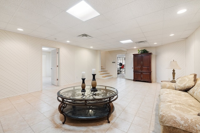 living room with a drop ceiling and light tile patterned floors