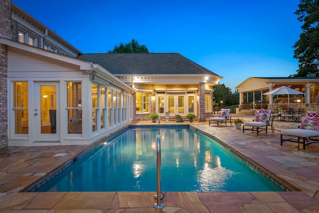 pool at dusk with a patio and french doors