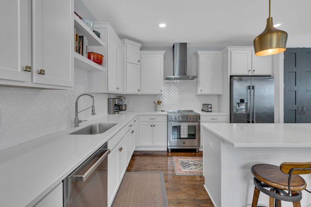 kitchen with dark hardwood / wood-style floors, sink, pendant lighting, wall chimney range hood, and appliances with stainless steel finishes