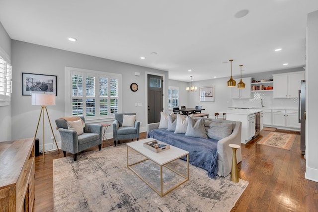 living room with a notable chandelier, sink, and dark wood-type flooring