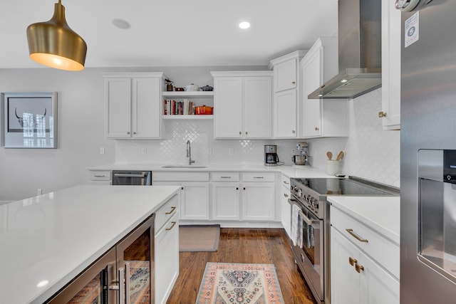 kitchen with dark hardwood / wood-style floors, white cabinets, sink, wall chimney range hood, and appliances with stainless steel finishes