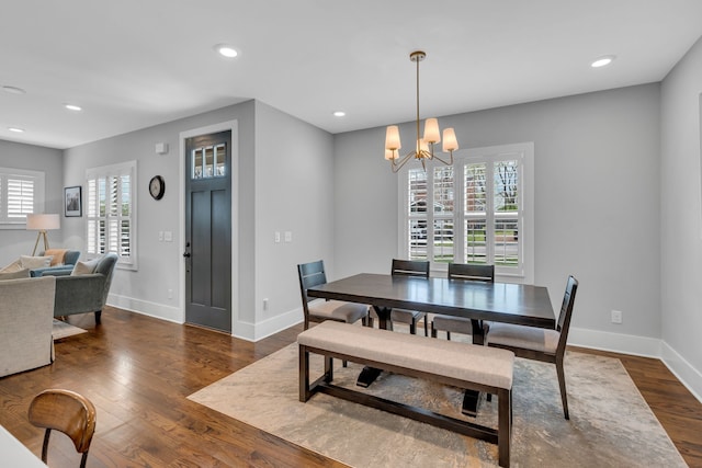 dining space with dark wood-type flooring and a notable chandelier