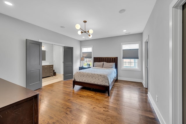 bedroom with multiple windows, an inviting chandelier, connected bathroom, and wood-type flooring