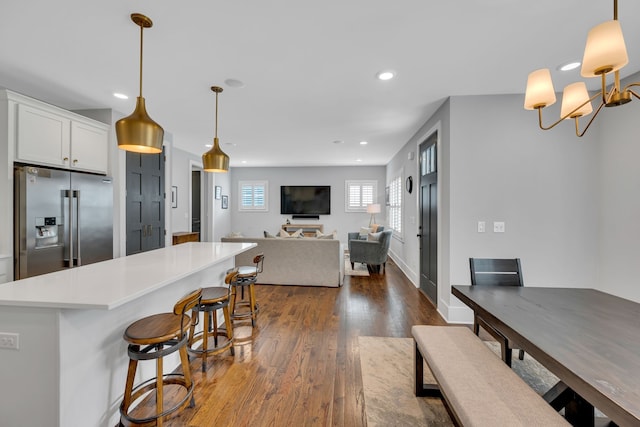 kitchen with white cabinets, decorative light fixtures, dark hardwood / wood-style flooring, and stainless steel fridge with ice dispenser