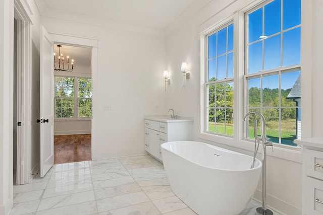 bathroom with a notable chandelier, vanity, ornamental molding, and a bath