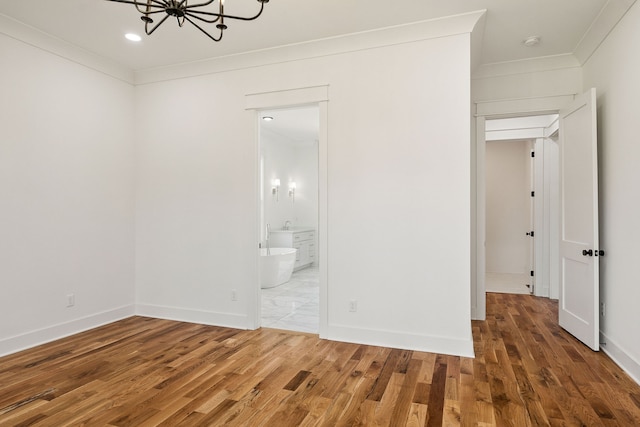 unfurnished bedroom with crown molding, connected bathroom, a chandelier, and dark hardwood / wood-style flooring