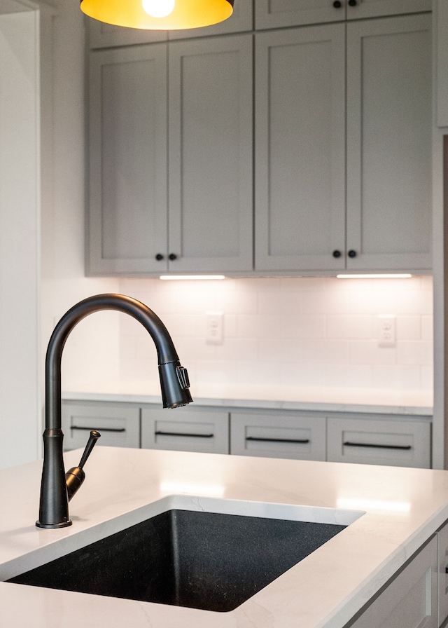 room details with decorative backsplash, sink, and gray cabinetry