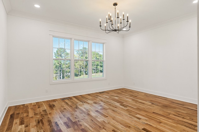 unfurnished room featuring ornamental molding, hardwood / wood-style floors, and an inviting chandelier