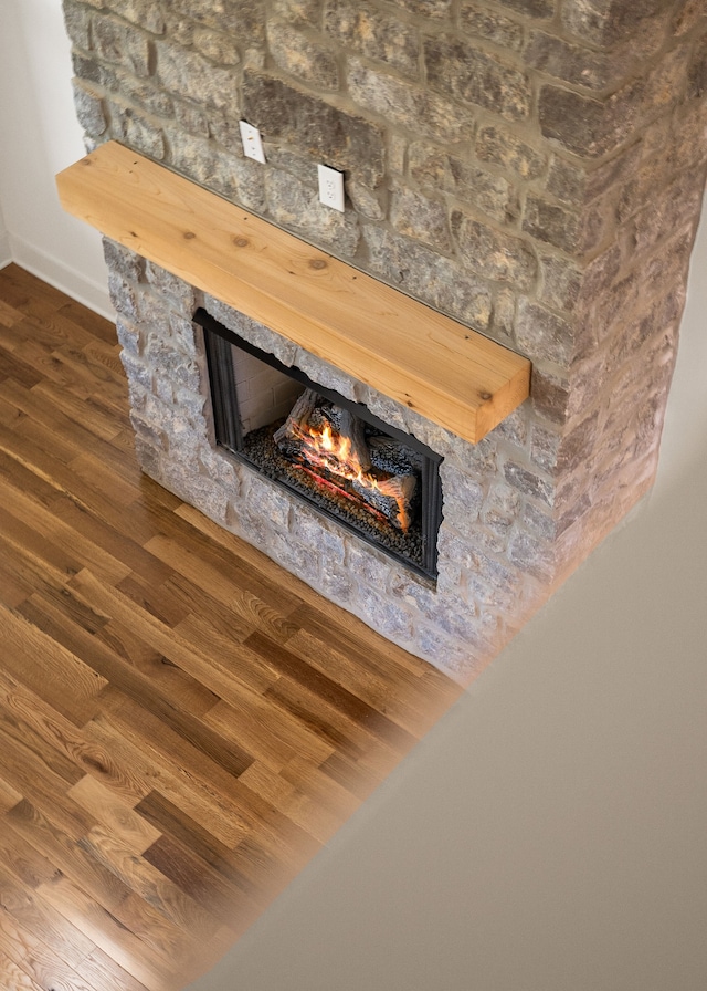 interior details featuring wood-type flooring and a stone fireplace