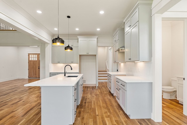 kitchen featuring an island with sink, sink, and light wood-type flooring