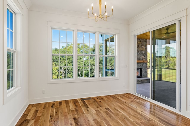 interior space featuring a fireplace, wood-type flooring, crown molding, and a notable chandelier