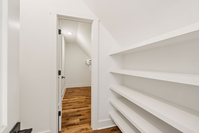 spacious closet with lofted ceiling and dark hardwood / wood-style floors