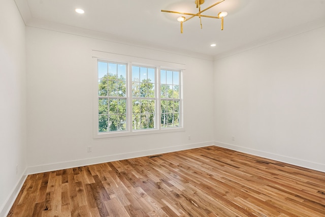 unfurnished room with crown molding, hardwood / wood-style floors, and an inviting chandelier