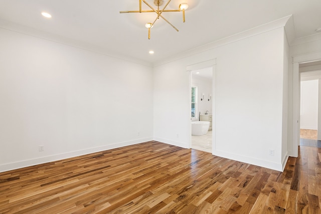 empty room with hardwood / wood-style flooring, crown molding, and a chandelier