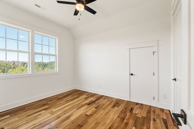 spare room featuring wood-type flooring, vaulted ceiling, and ceiling fan