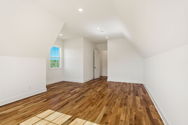 additional living space with wood-type flooring and vaulted ceiling