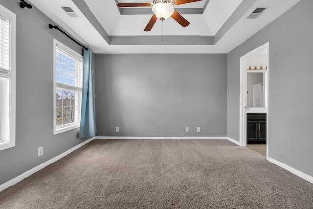 carpeted empty room featuring a tray ceiling and ceiling fan