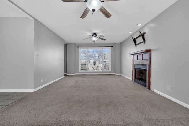 unfurnished living room featuring carpet floors, ceiling fan, and a tile fireplace