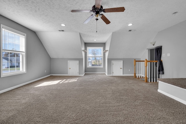 additional living space with a textured ceiling, plenty of natural light, vaulted ceiling, and carpet floors