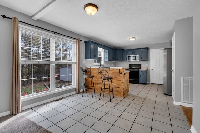 kitchen with stainless steel appliances, blue cabinets, kitchen peninsula, light tile patterned floors, and a breakfast bar area