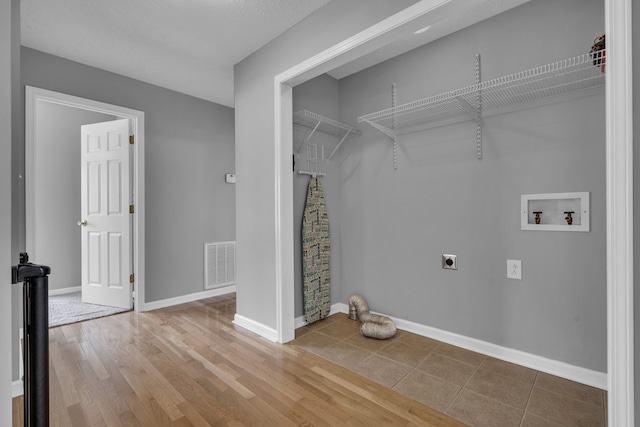 clothes washing area featuring a textured ceiling, hookup for a washing machine, electric dryer hookup, and hardwood / wood-style flooring