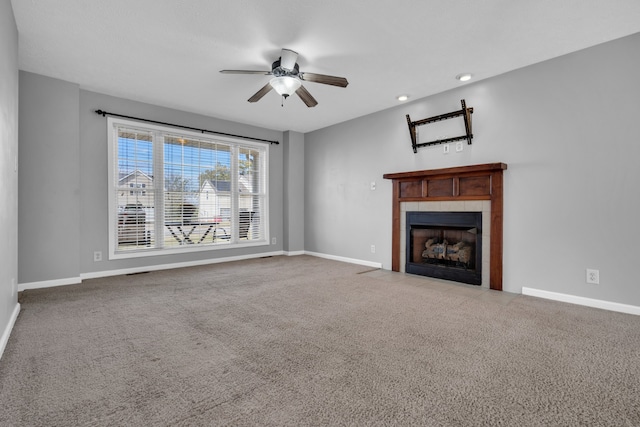 unfurnished living room featuring a tiled fireplace, carpet flooring, and ceiling fan