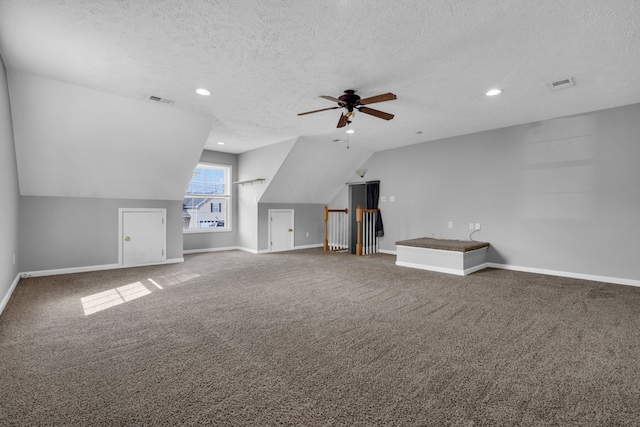 additional living space with carpet, a textured ceiling, vaulted ceiling, and ceiling fan