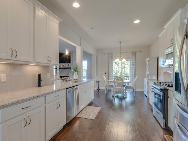 kitchen featuring sink, light stone counters, dark hardwood / wood-style floors, white cabinets, and appliances with stainless steel finishes