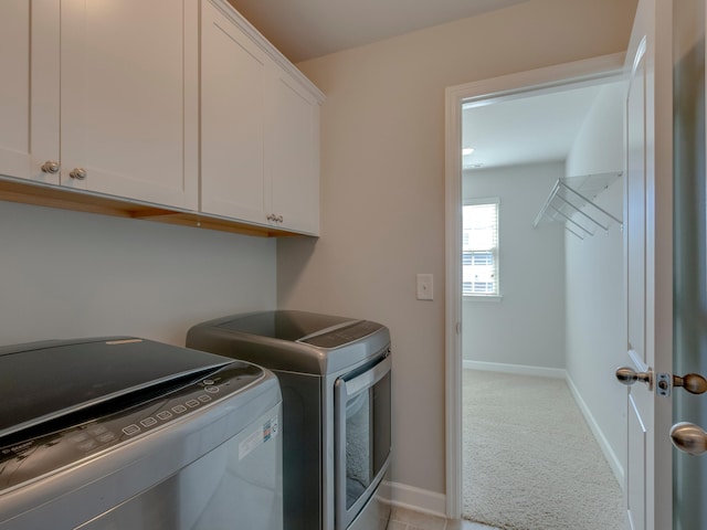 washroom with washing machine and clothes dryer, cabinets, and light carpet