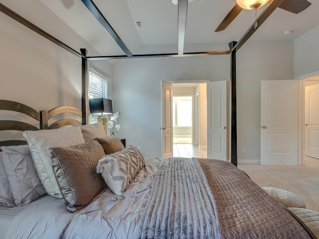 bedroom featuring beam ceiling, light carpet, and ceiling fan