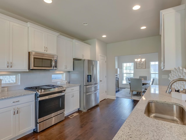 kitchen with dark hardwood / wood-style flooring, sink, light stone countertops, white cabinets, and appliances with stainless steel finishes